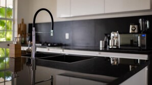 A modern kitchen with a sleek black countertop, stainless steel appliances, and a black faucet. - Artiko Luxury Suites - Jan Thiel (Jan Thiel)