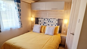 Une chambre à coucher comprenant un lit, deux tables de chevet, une commode, une armoire et une fenêtre avec des rideaux.