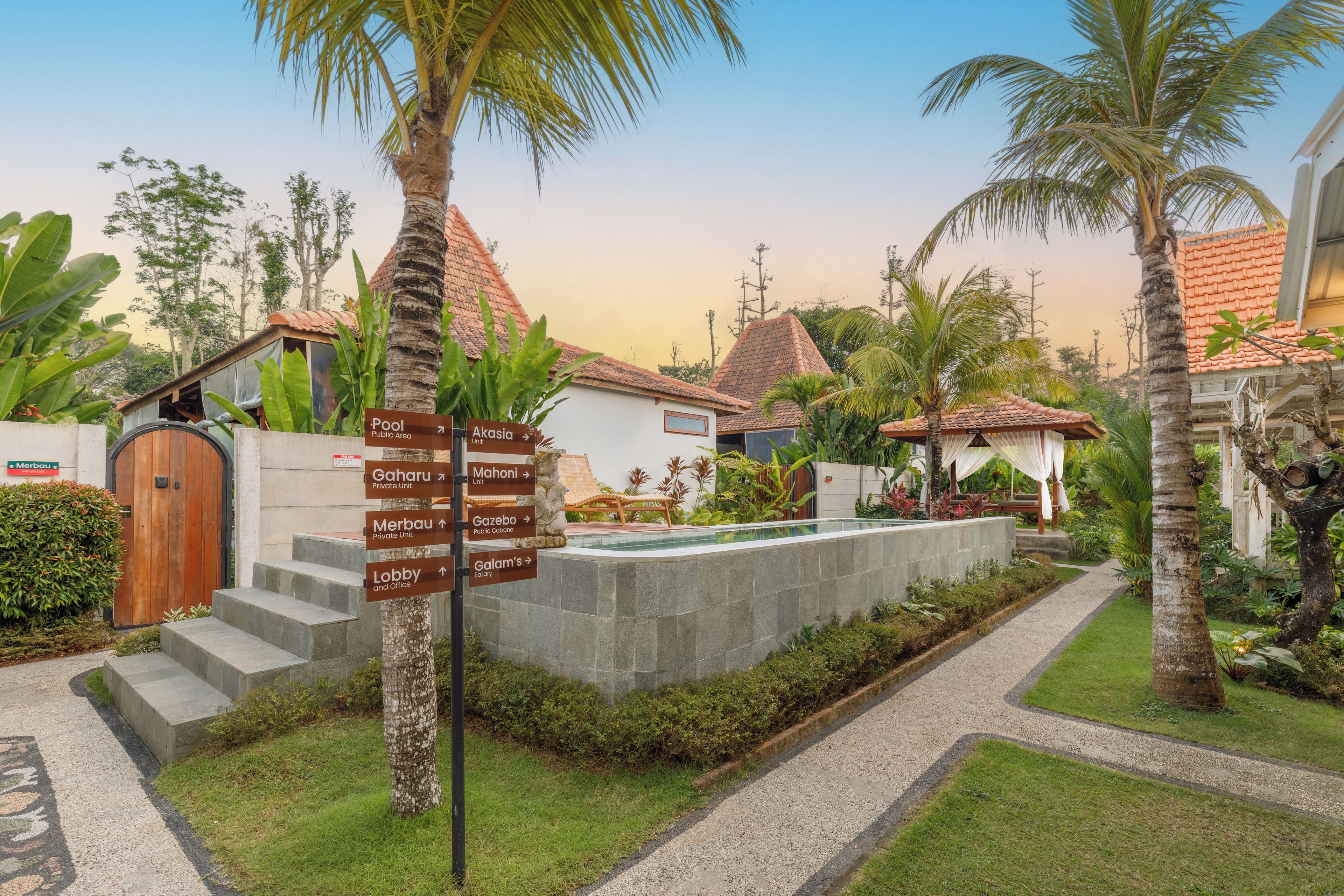 A resort with a pool, palm trees, and a signpost with directions to various amenities.