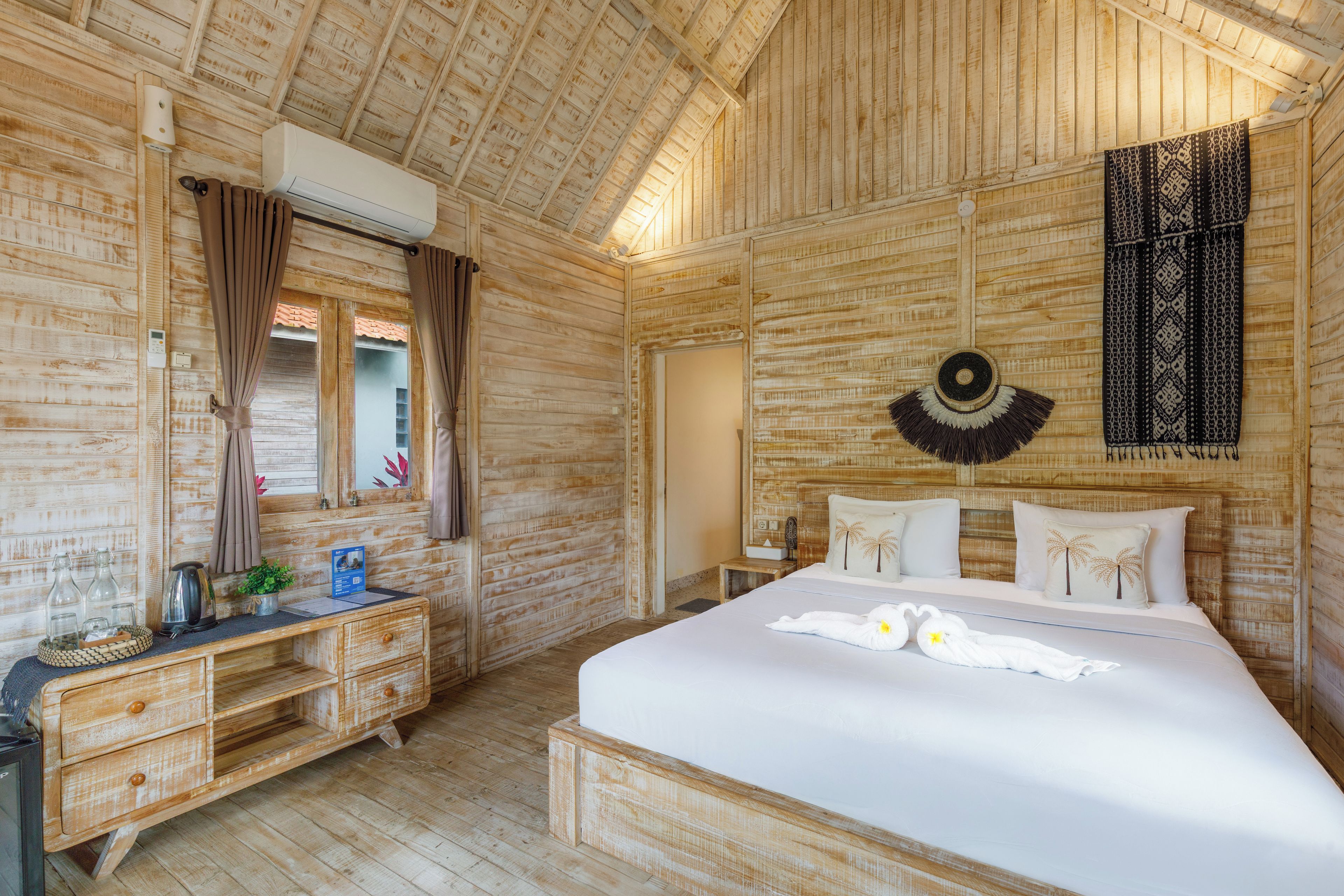 Een houten kamer met een bed, een kaptafel met spiegel en een wandairconditioner.