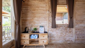 A wooden cabin room with a wooden dresser, curtains, and a window overlooking a balcony. - Bale Taru Pecatu  (Pecatu)