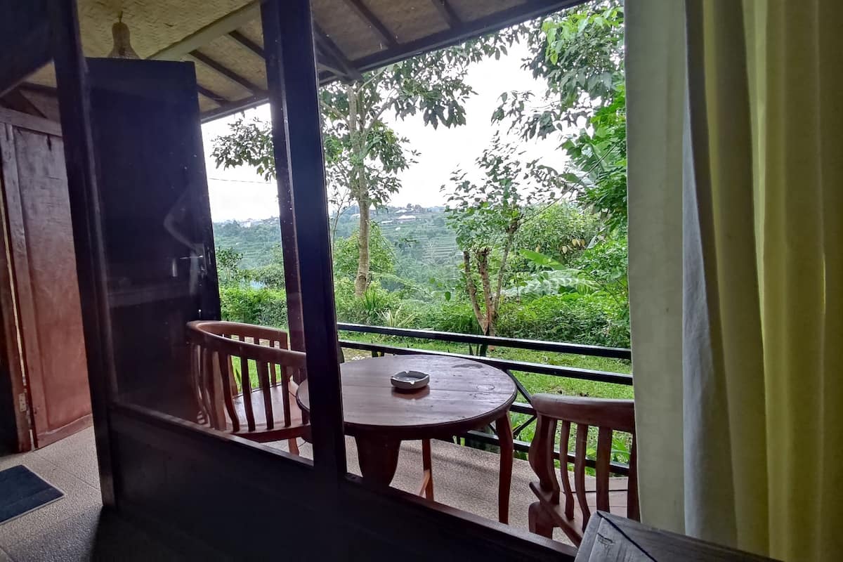 Un balcón con mesa y sillas, con vista a un paisaje verde y exuberante.