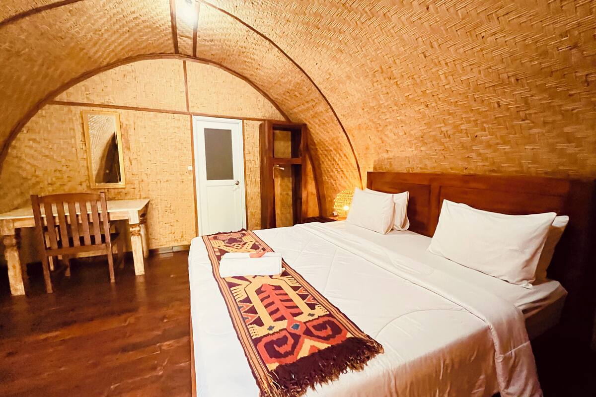 Una habitación con una cama grande, un escritorio de madera y una silla.