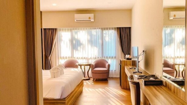 Une chambre d’hôtel avec un lit, un bureau, une chaise et un grand miroir.