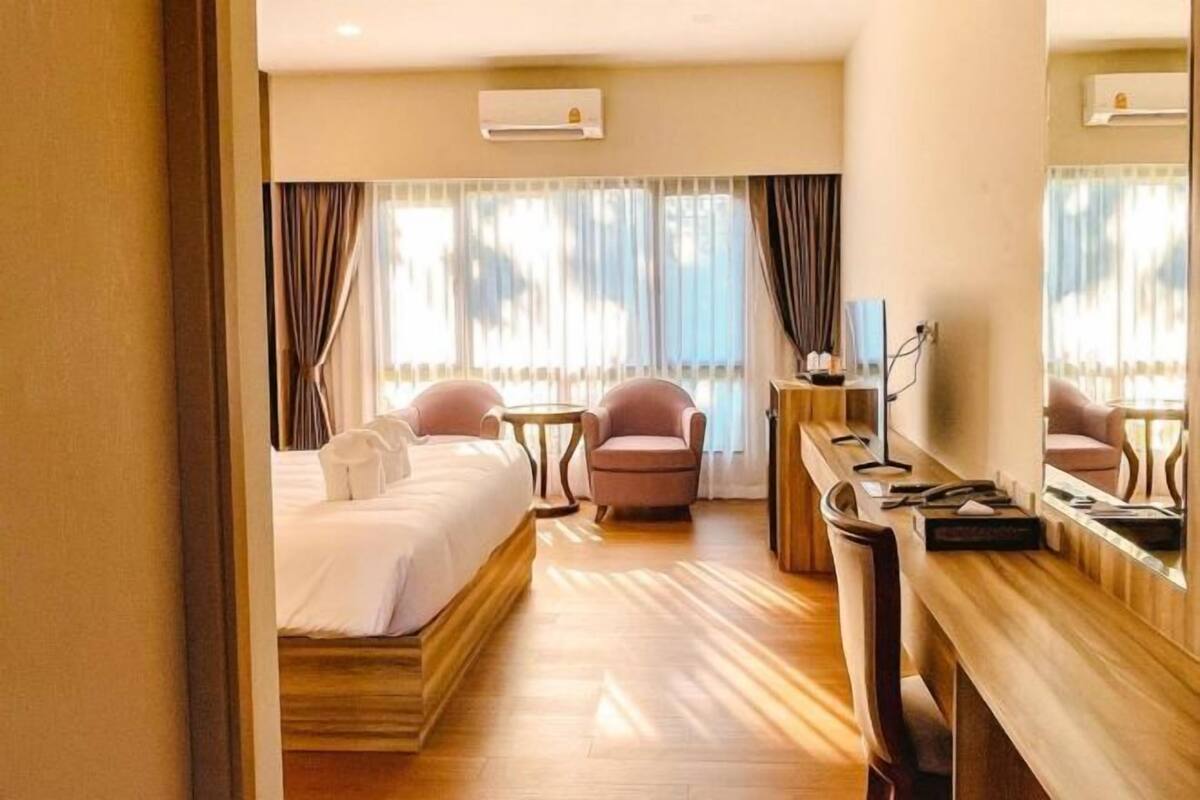 A hotel room with a bed, a desk, a chair, and a large mirror.