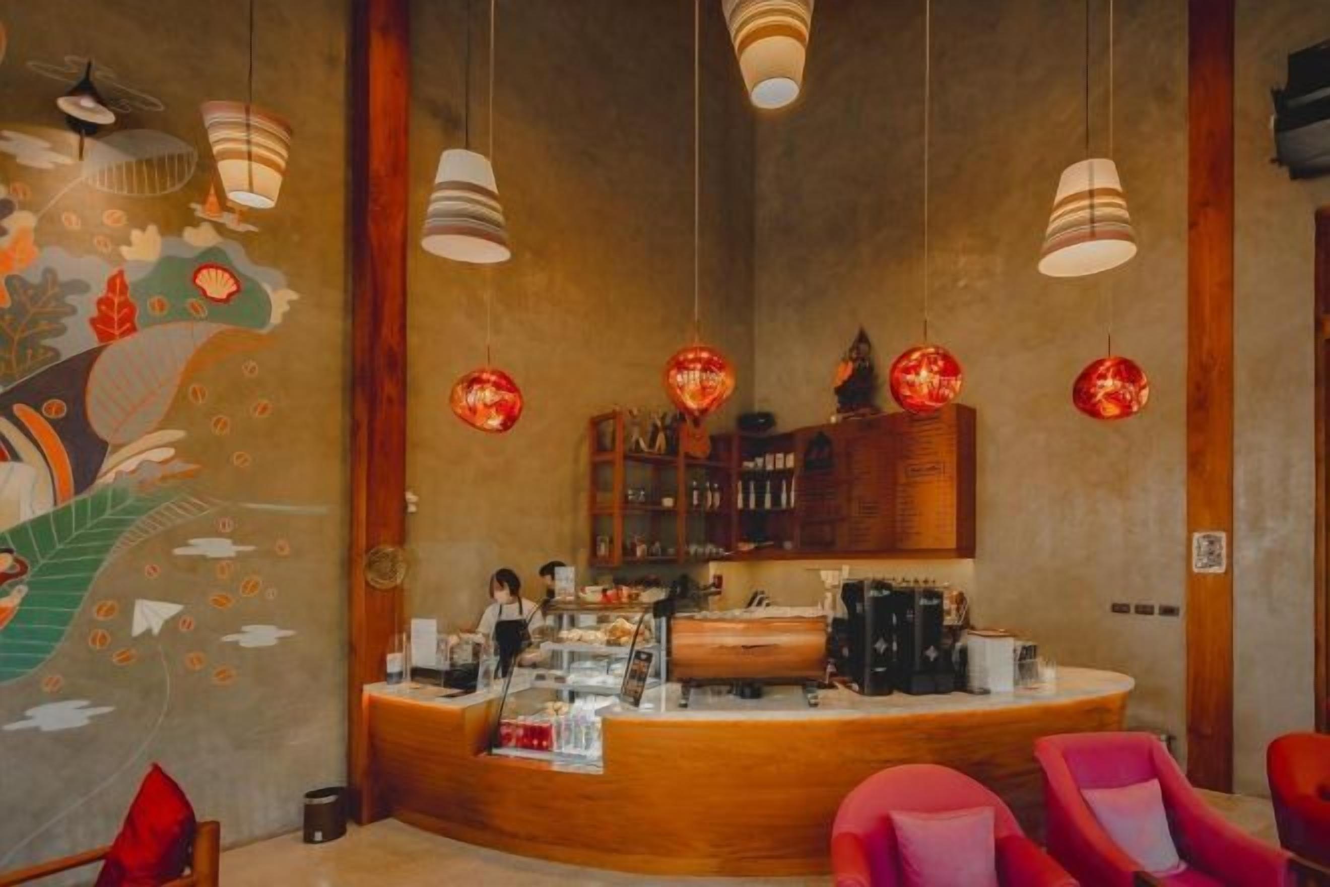Interior de un restaurante con mostrador, luces colgantes y un mural en la pared.