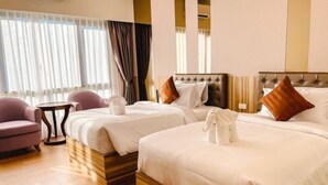 Une chambre d’hôtel avec deux lits, une petite table, une chaise et une fenêtre avec des rideaux.