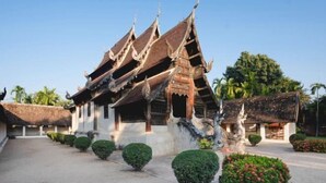 A traditional Thai temple with ornate architecture, including a multi-tiered roof and a central statue.