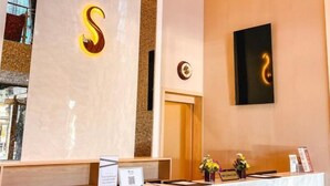 A reception desk with a large illuminated 'S' sign, a clock, and a framed artwork on the wall.