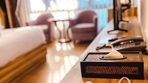 A hotel room with a bed, a desk with a computer, and a window with curtains.