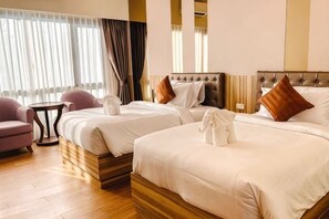 A hotel room with two beds, a sitting area with a chair, a small table, and a window with curtains. - Sukruethai Hotel Chiang Mai (Hang Dong)