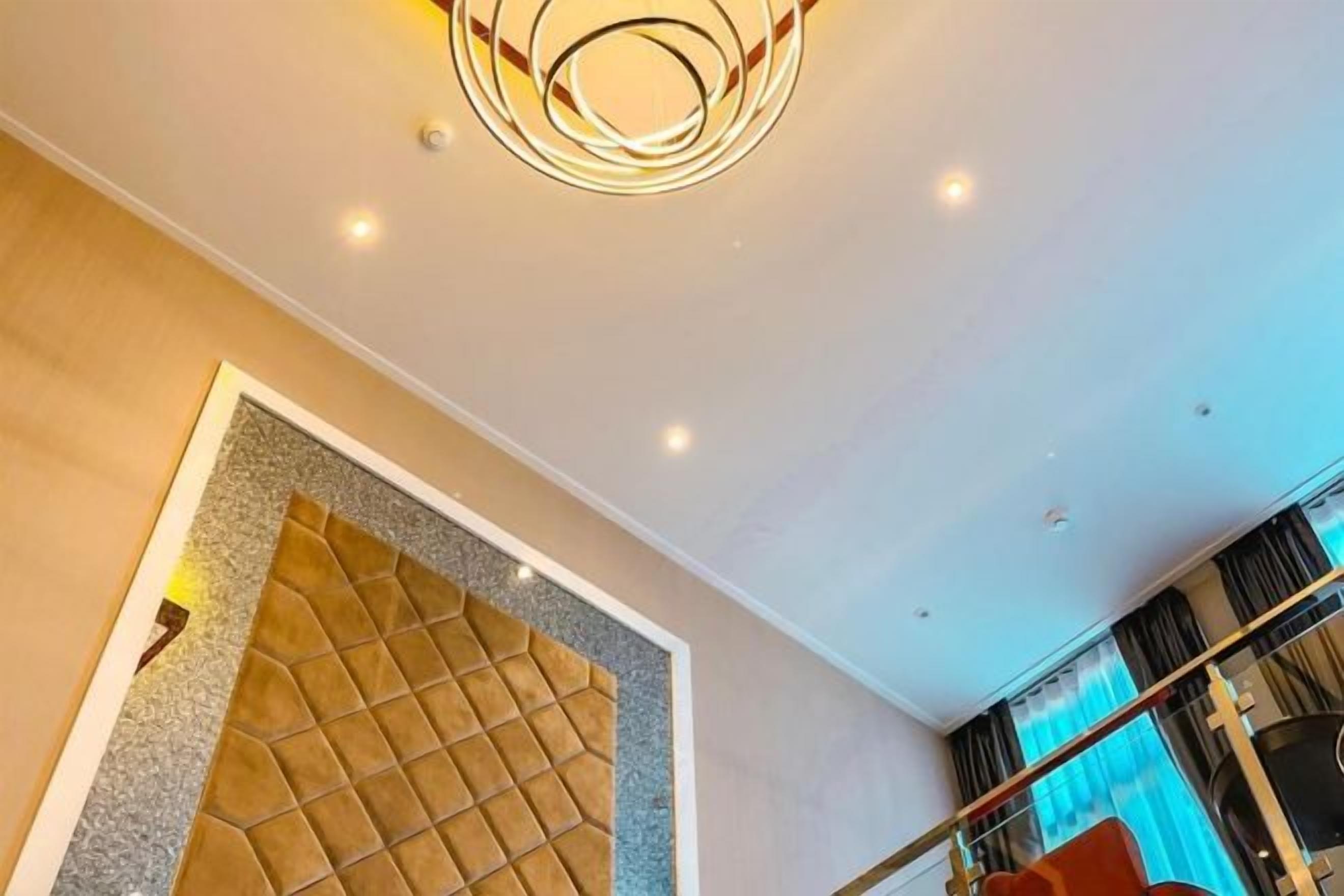 A modern interior with a geometric wall design, recessed ceiling lighting, and a visible window with curtains.