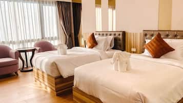 Habitación de hotel con dos camas, una mesita redonda pequeña, una silla y un ventanal grande con cortinas.