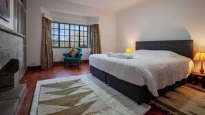 Ein Hotelzimmer mit einem großen Bett, einem Sessel, einem Kamin und Blick durch ein Fenster.