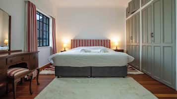Un dormitorio con cama, mesitas de noche, cómoda y armario.