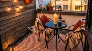 A cozy outdoor seating area with a table, chairs, a candle, and a bottle of wine. - Panoramic Two-bedroom Penthouse (Cork)
