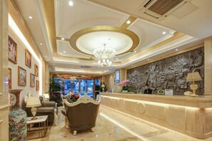 Una hall d'albergo con reception, area salotto e lampadario.