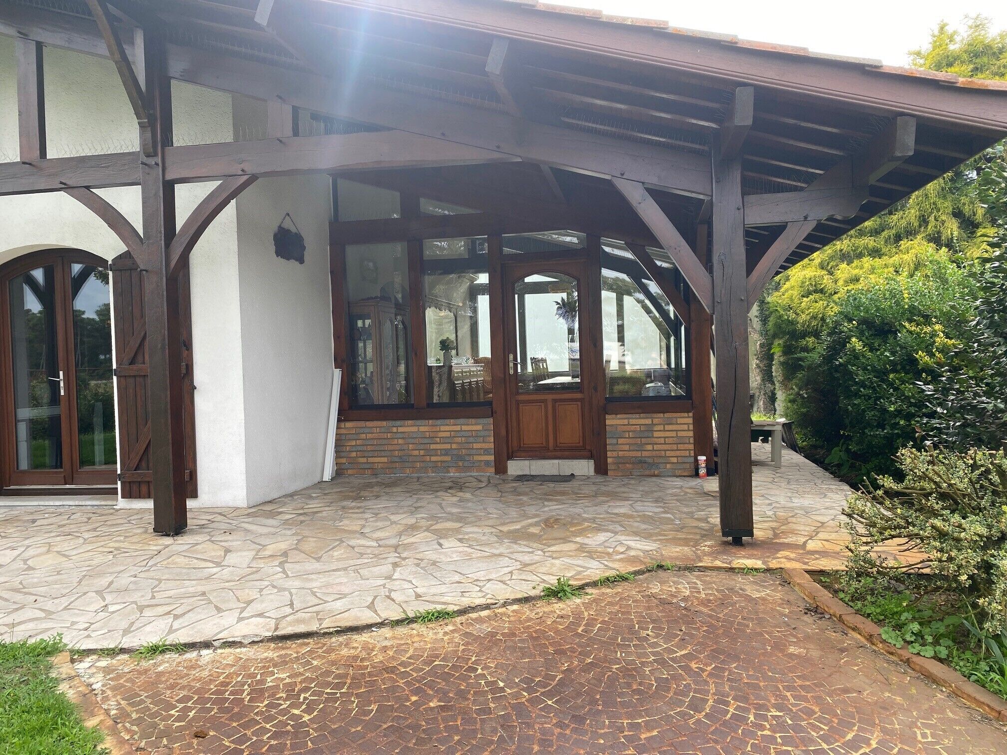 A covered patio area with stone flooring and wooden beams.