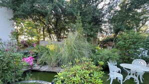 A garden with a pond, white metal chairs, and various plants. - Jade room (Rosières)