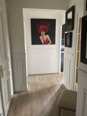 Stylish hallway with a door leading to a room, adorned with a framed painting and a bench.