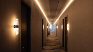 Ein Hotelgang mit beleuchteten Wandleuchten, Teppichboden und Türen auf beiden Seiten.
