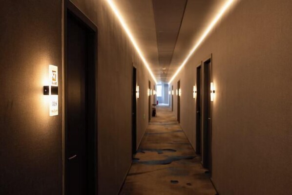 A hotel hallway with illuminated wall sconces, a carpeted floor, and doors on both sides. - Mitian Business Motel (Ningbo)