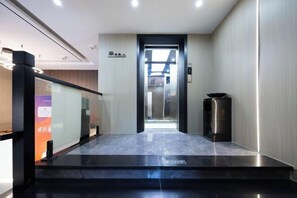 A modern elevator with a glass door, leading to a well-lit interior. - Mitian Business Motel (Ningbo)