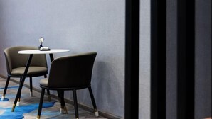Habitación de hotel moderna con diseño minimalista, que incluye dos sillas negras y una pequeña mesa blanca.