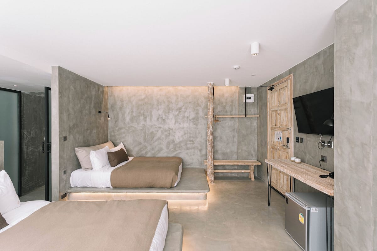 Une chambre moderne avec deux lits, un téléviseur intégré et une petite kitchenette.