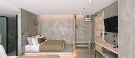 A modern bedroom with two beds, a built-in TV, and a small kitchenette.