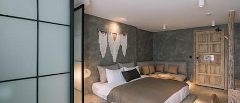 Quarto moderno com uma cama grande, uma porta de madeira e uma decoração de macramé na parede.