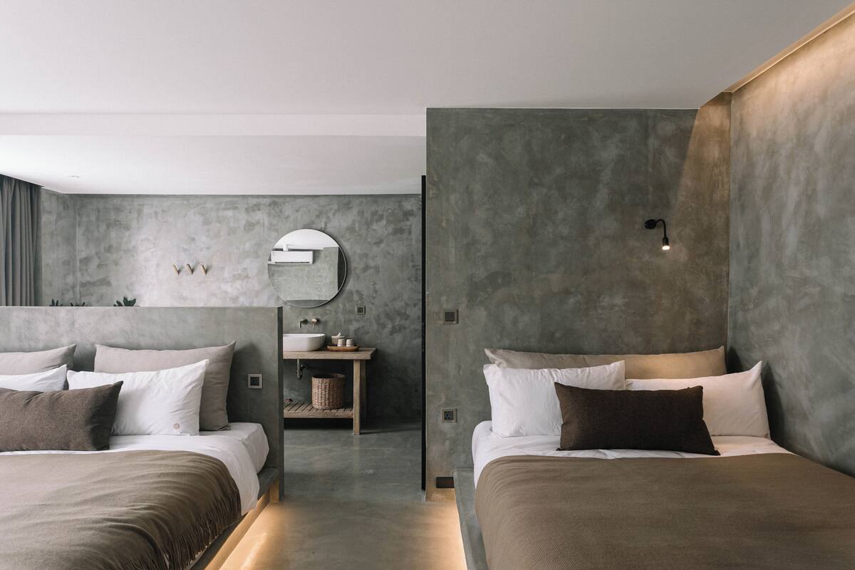Une chambre moderne avec deux lits, un grand miroir et un lavabo intégré.
