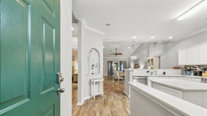 Une cuisine moderne avec des meubles blancs, un plancher en bois et une porte verte.