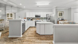 Une cuisine moderne avec des meubles blancs, un îlot central et un plancher en bois.