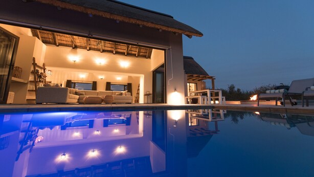 Een modern huis met zwembad, een eethoek en een woonkamer met een bank en televisie.