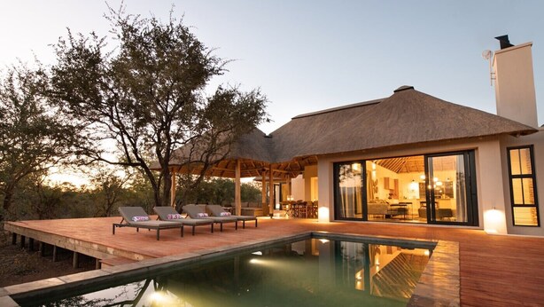 A modern house with a swimming pool, lounge chairs, and a dining area. - Villa Scarabee: Wonderful luxury villa in the middle of nature (Hoedspruit)