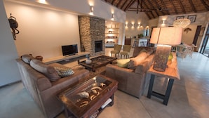 Amplia sala de estar con chimenea de piedra, sofás de cuero y una mesa de centro con objetos decorativos.