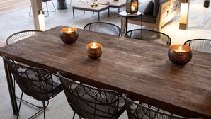 An outdoor dining area with a wooden table, black wire mesh chairs, and candles. - Meet Villa Safari: a 5-star exclusive villa (Hoedspruit)