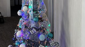 A Christmas tree with lights and ornaments in a room with a white door and a sign that reads "Heaven". - Historic Harkers Island Bungalow (Harkers Island)