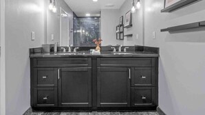Un bagno moderno con un mobile doppio lavabo, mobili scuri e uno specchio grande.
