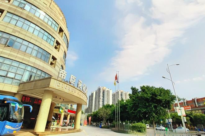 A hotel entrance with a curved facade, a flag, and a clear sky.