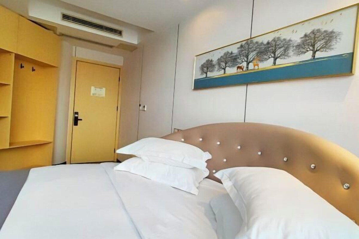 A hotel room with a bed, a painting on the wall, and a door to a closet.