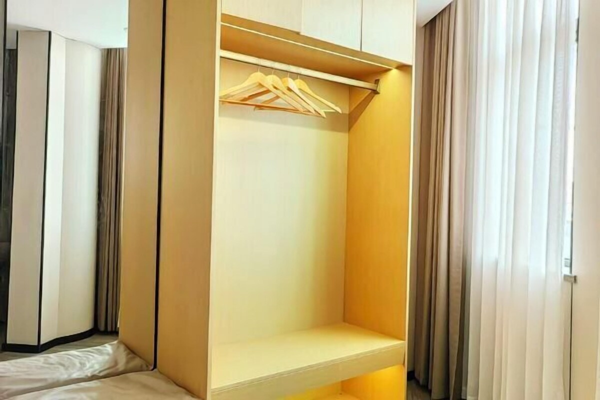 A walk-in closet with a wooden hanger rod and a shelf.