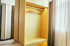 A walk-in closet with a wooden hanger rod and a shelf. - Chongqing Dichen Garden Hotel (Chongqing)