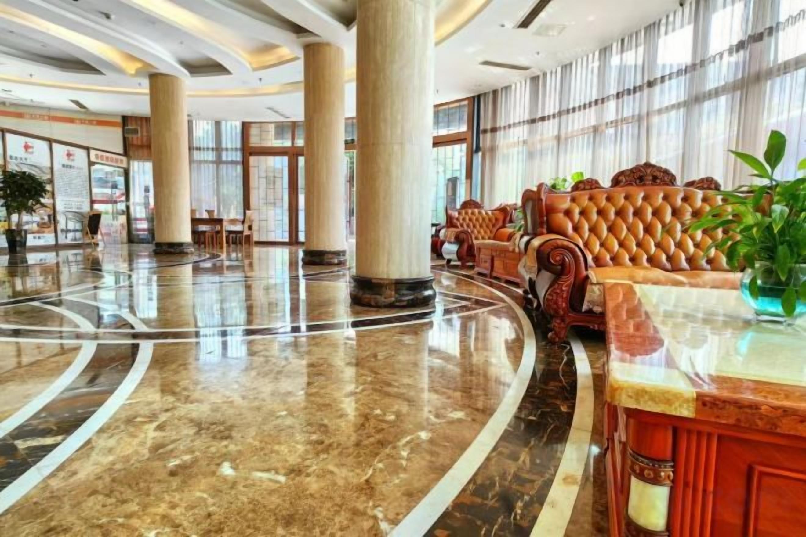 A spacious lobby with a marble floor, large columns, and a seating area with ornate sofas.