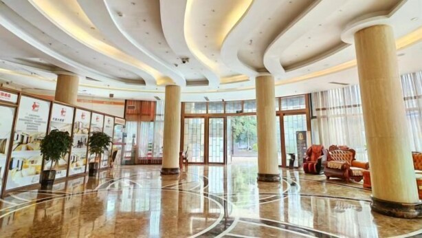 Un vestíbulo espacioso con piso de mármol pulido, amplias columnas y un diseño de techo curvo.
