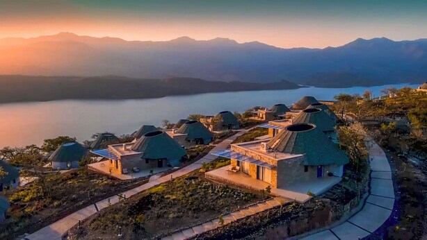 A cluster of dome-shaped buildings with a view of a lake and mountains in the background. - Halala Kella Eco Lodge (Zima)