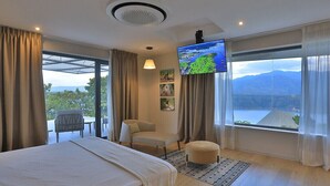 A hotel room with a bed, a TV, a chair, and a view of mountains. - Halala Kella Eco Lodge (Zima)
