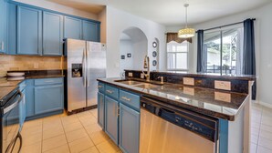 Eine moderne Küche mit blauen Schränken, Edelstahlgeräten und einer Arbeitsplatte aus Granit.