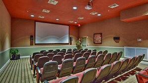 Ein Konferenzraum mit Reihen von Stühlen, einer Projektionsleinwand und einem großen Fenster mit Jalousien.
